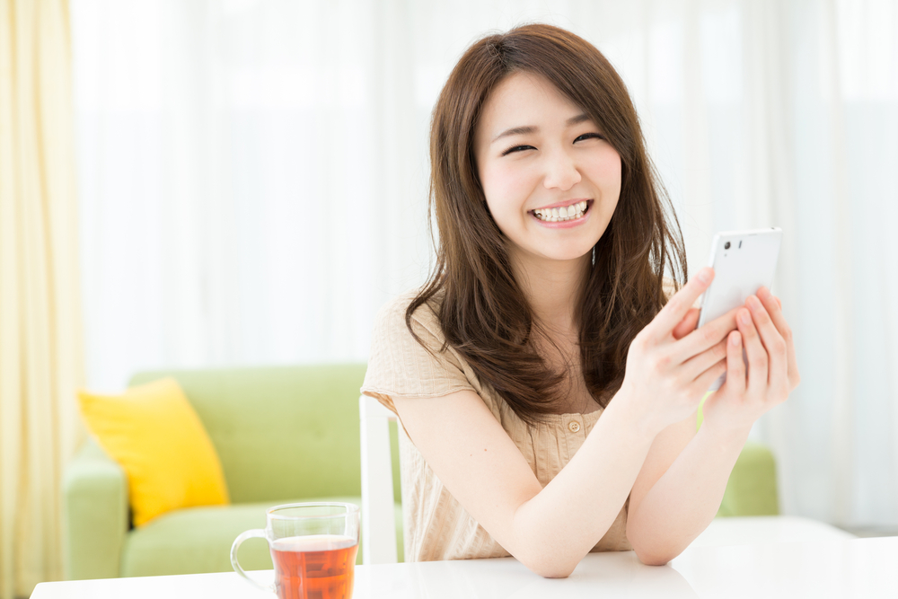 スマホを手に笑顔の女性